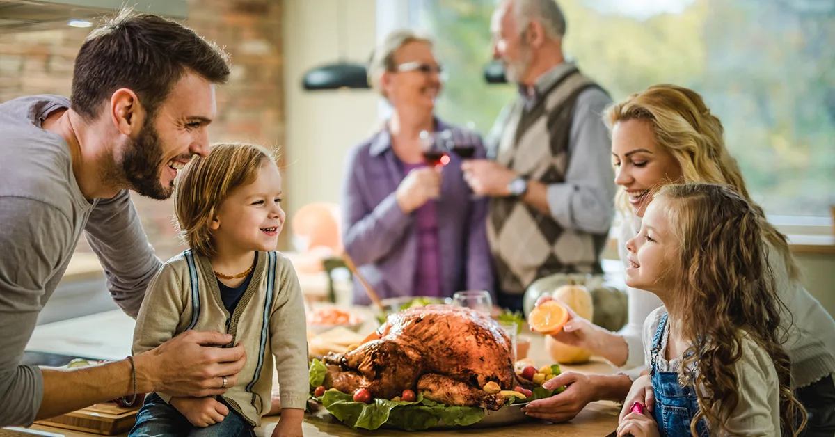 A family stands in front of a turkey dinner with a large window in the background that can be protected with residential window tint to stop heat and glare.