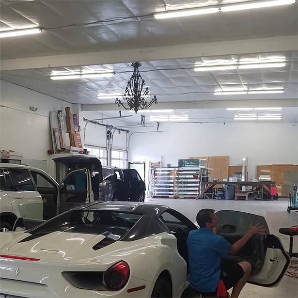 A look inside Advanced Window Tinting’s tint shop in Jacksonville as an employee installs tint on two white vehicles.