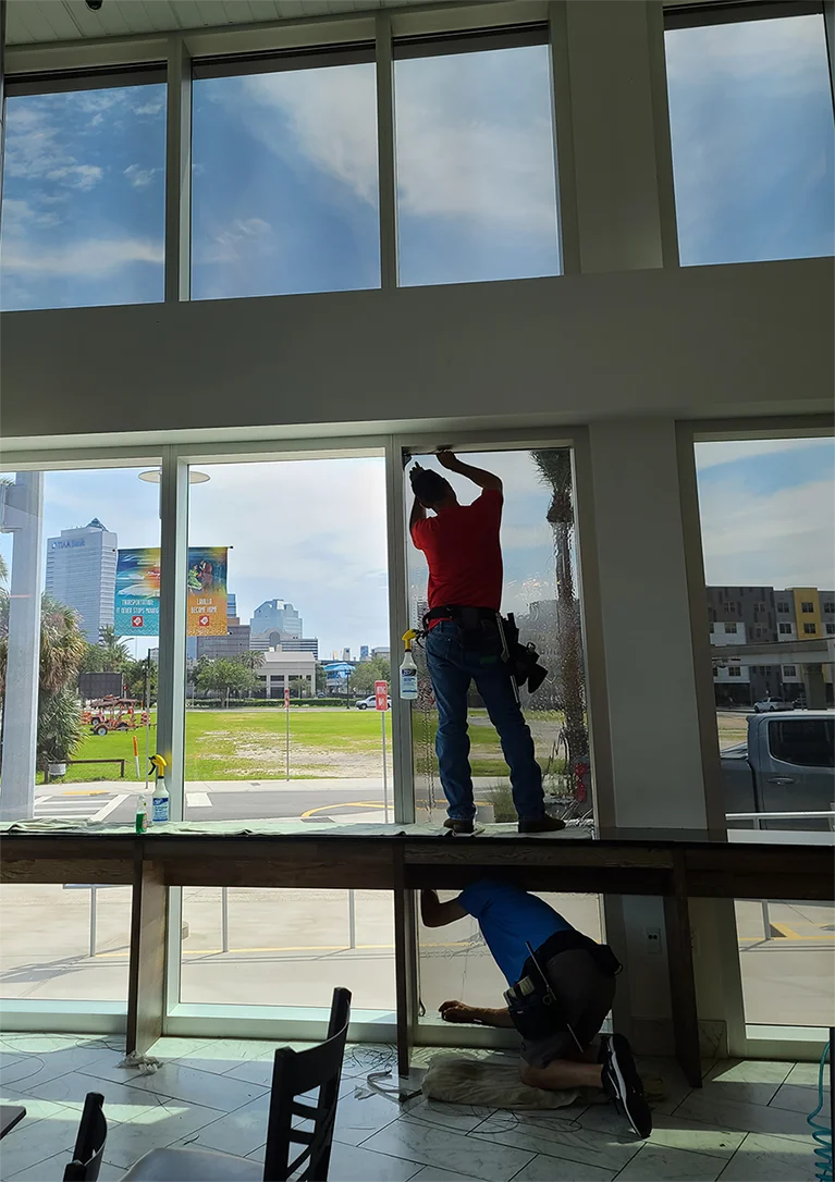 Two professional installers from Advanced Window Tinting add 3M Window Film to the glass on the Jacksonville Transportation Authority’s building.