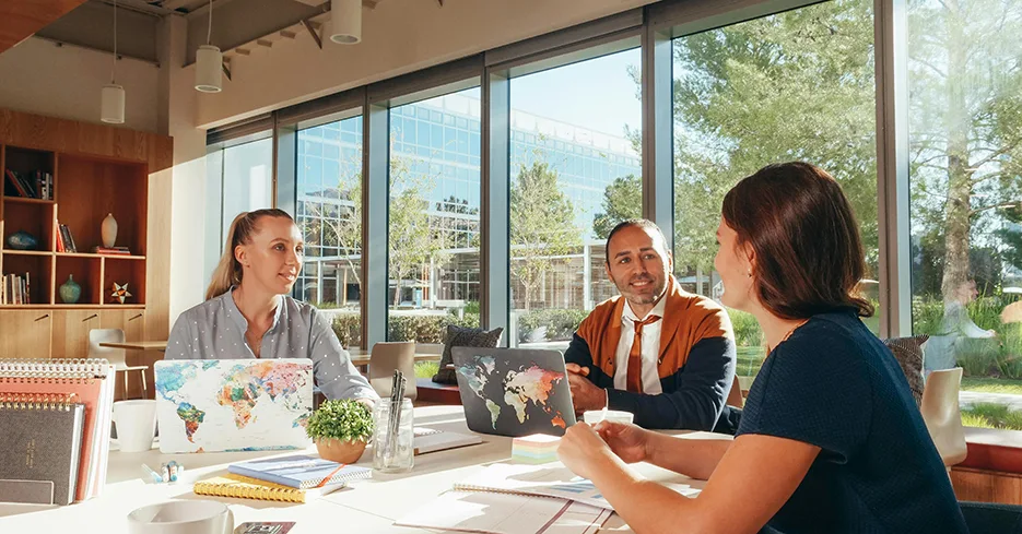 Employees comfortably participate in a meeting next to large bay windows.
